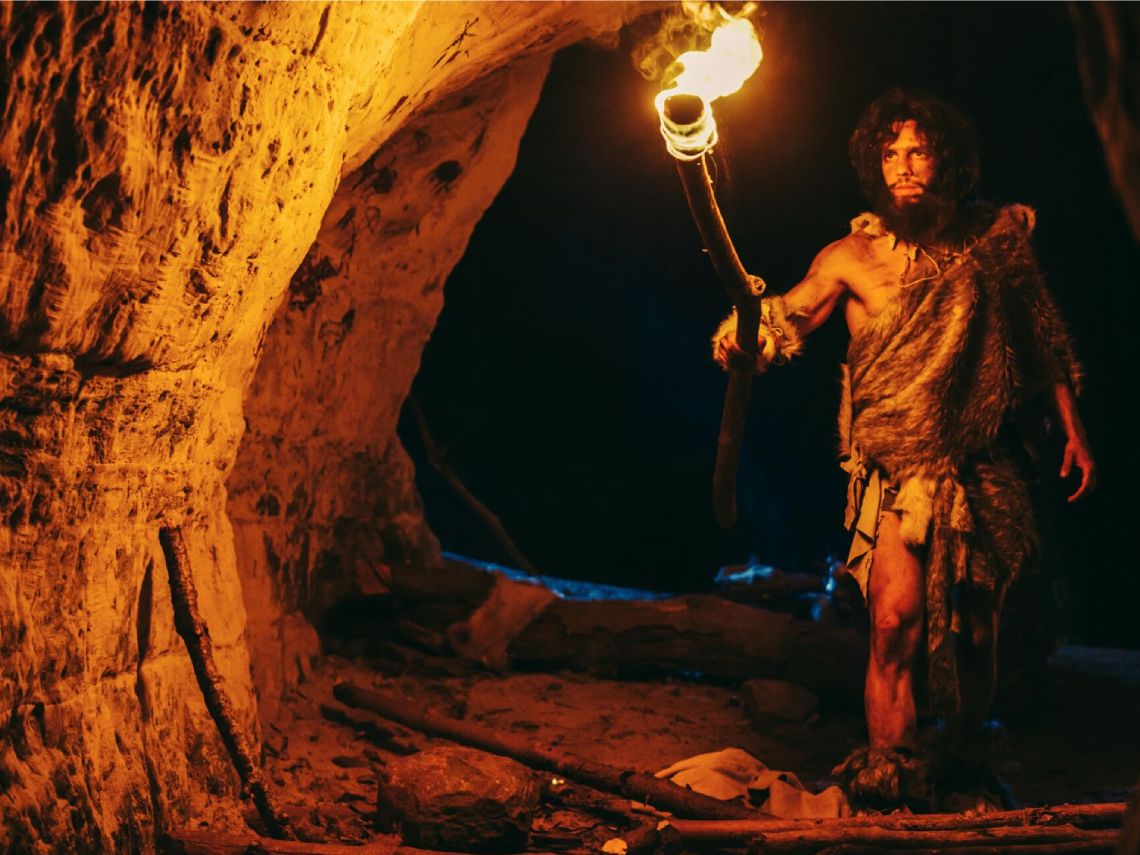 Hombre primitivo en una cueva con una antorcha.