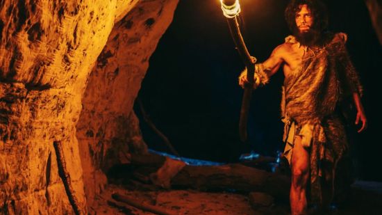 Hombre primitivo en una cueva con una antorcha.