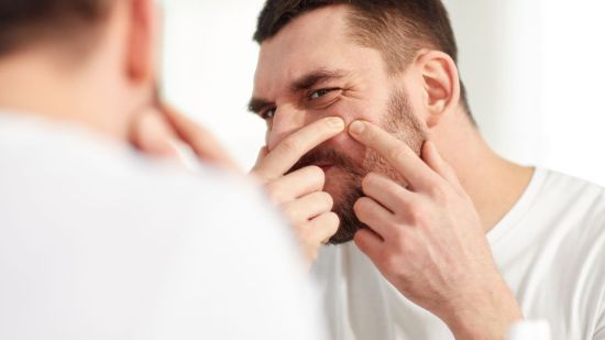 Hombre quitándose granos de la barba