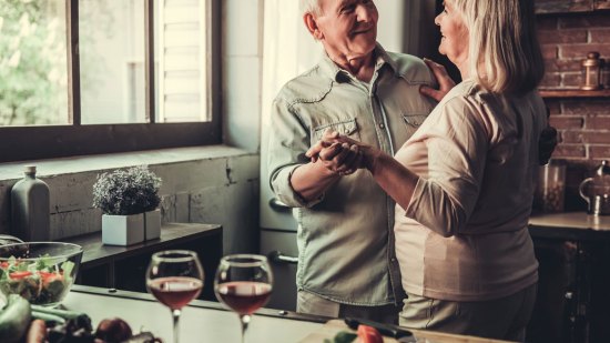 pareja ancianos bailan y beben vino
