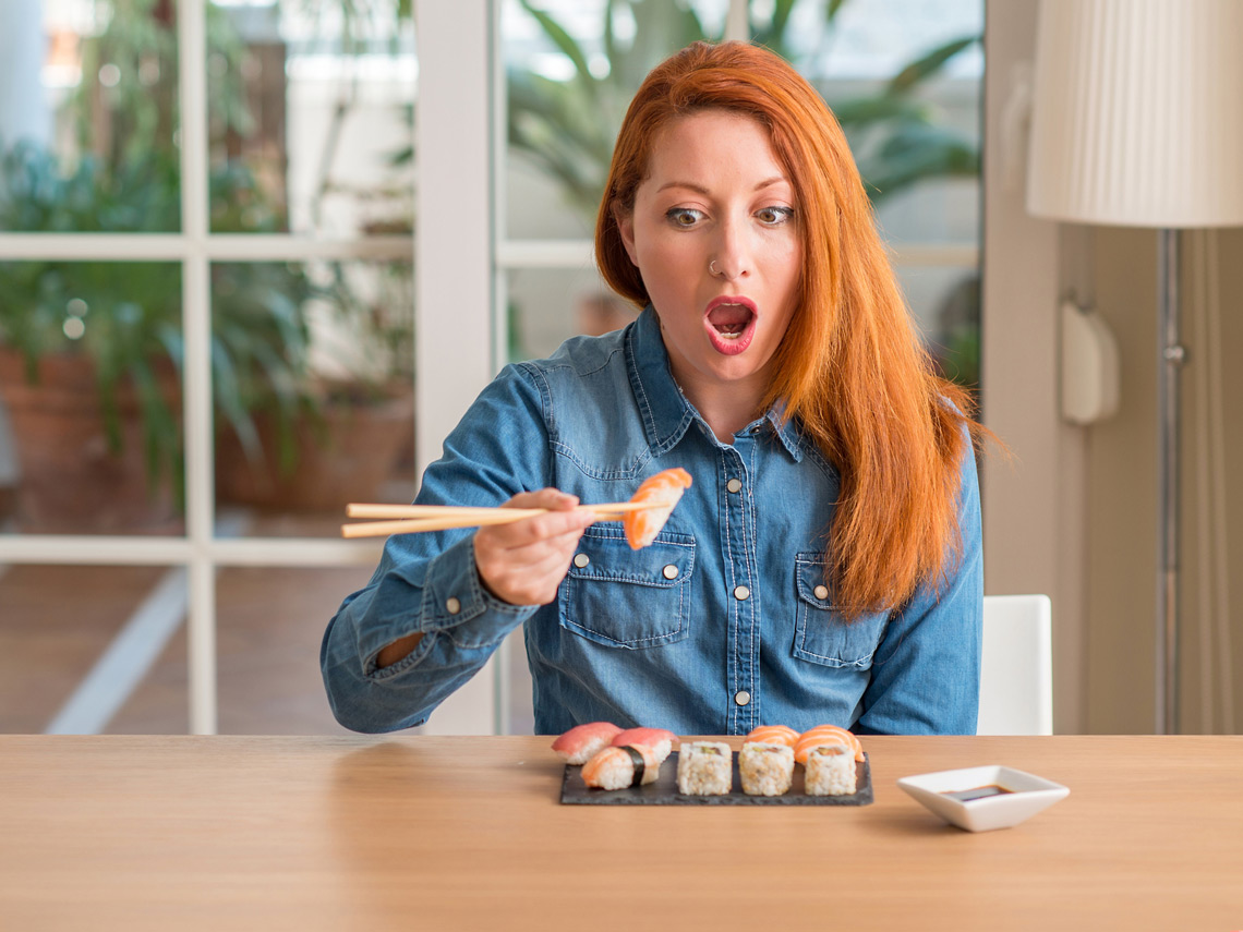 Mujer pelirroja comiendo sushi
