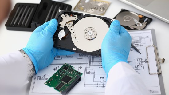 Technician repairs computer hard drive from motherboard.