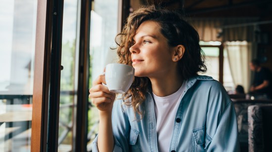 Mujer pensando en la vida mientras toma un café