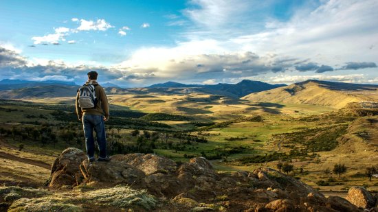 Hombre observando un paisaje en la cima de una montaña