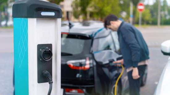 man-plugging-charger-into-electric-car-charge-station-scaled