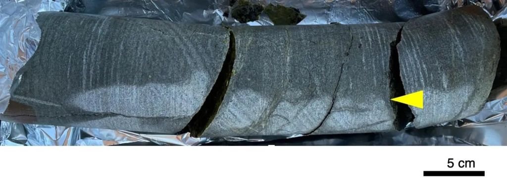 Esta fotografía fue tomada en el lugar cuando la muestra del núcleo de perforación fue lavada, flameada y luego agrietada. El núcleo de 30 centímetros de largo y 85 milímetros de diámetro fue llevado de regreso a Japón para su estudio posterior.