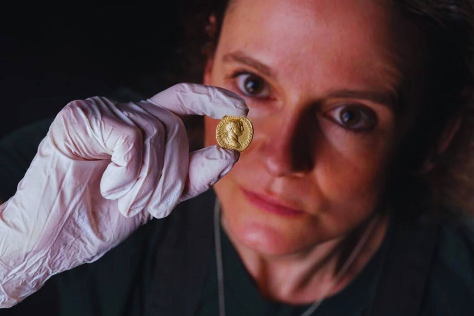 La conservadora Bethan Bryan analiza cuidadosamente el aureus de oro acuñado durante el reinado de Trajano