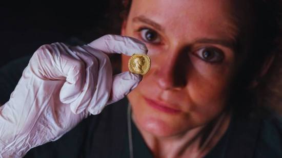 La conservadora Bethan Bryan analiza cuidadosamente el aureus de oro acuñado durante el reinado de Trajano