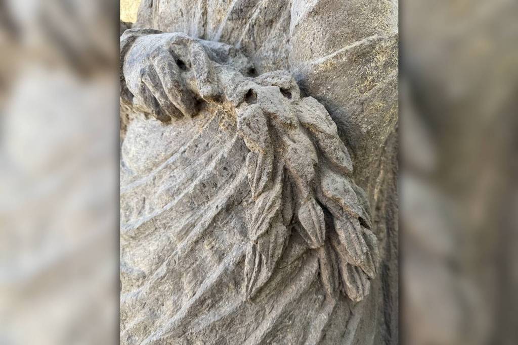 La figura femenina sostiene un ramo de laurel, una planta que los sacerdotes y sacerdotisas romanos empleaban en rituales de purificación de espacios sagrados