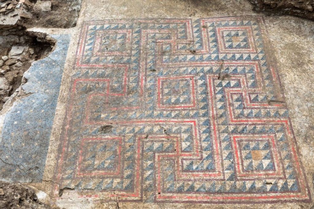 Vista general del mosaico, enmarcado por tres lados con zonas blancas sin decoración y, en su lado izquierdo, por un rectángulo negro que podría señalar el umbral de una antigua puerta