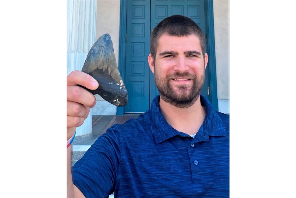 El biólogo de la Universidad de California en Riverside, Phillip Sternes, primer autor del estudio, sostiene un diente fósil de megalodón entre sus manos