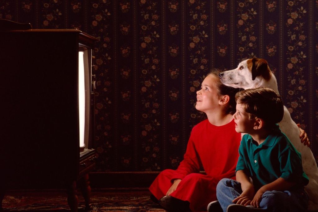 Un grupo de niños viendo la televisión con su perro