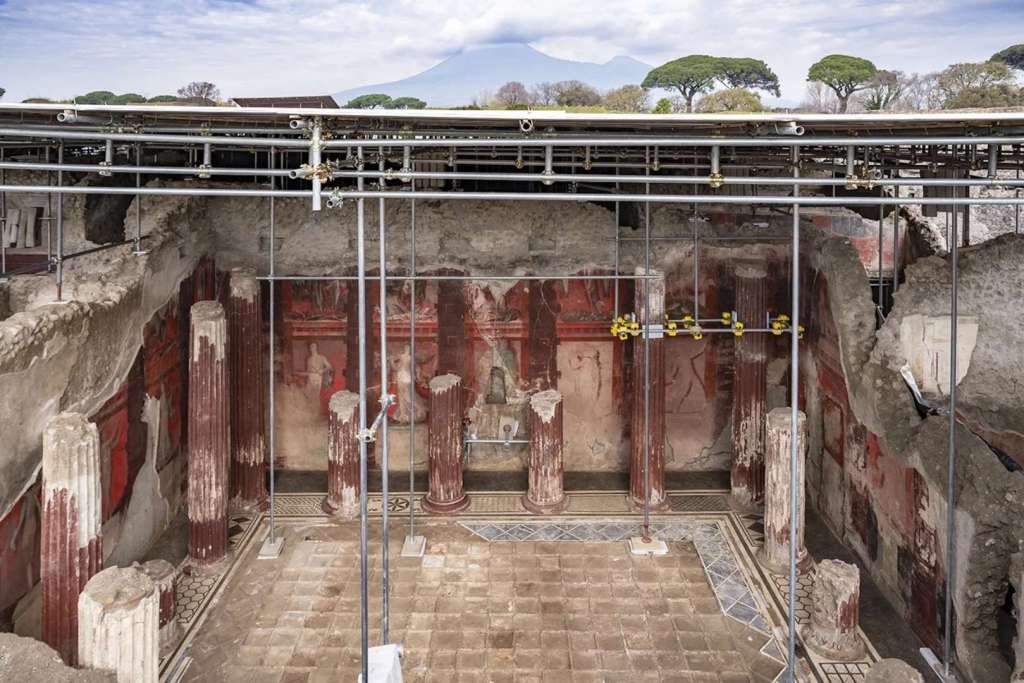 Oculto tras antiguas columnas erosionadas por el tiempo, un imponente mural dionisíaco se despliega a lo largo de tres paredes de un antiguo salón de banquetes en la Insula 10 de la Regio IX, en el corazón de Pompeya