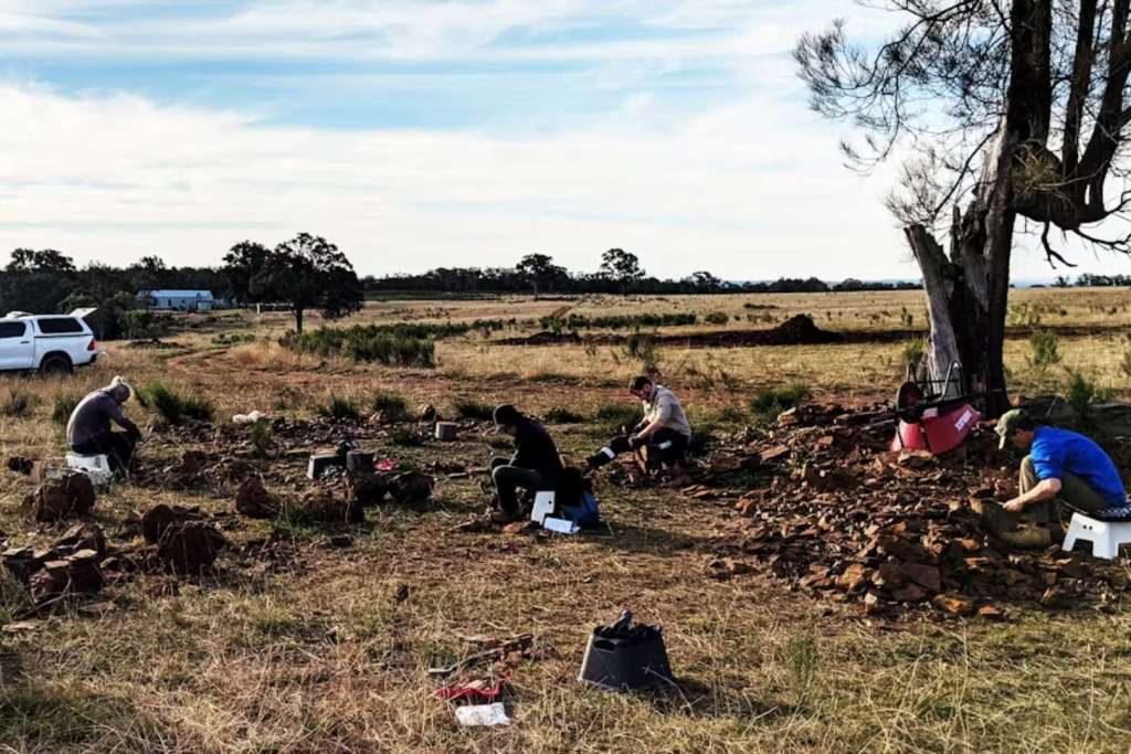 Un equipo de paleontólogos del Australian Museum trabaja en McGraths Flat, rompiendo las rocas rojas con martillo y cincel en busca de fósiles ocultos