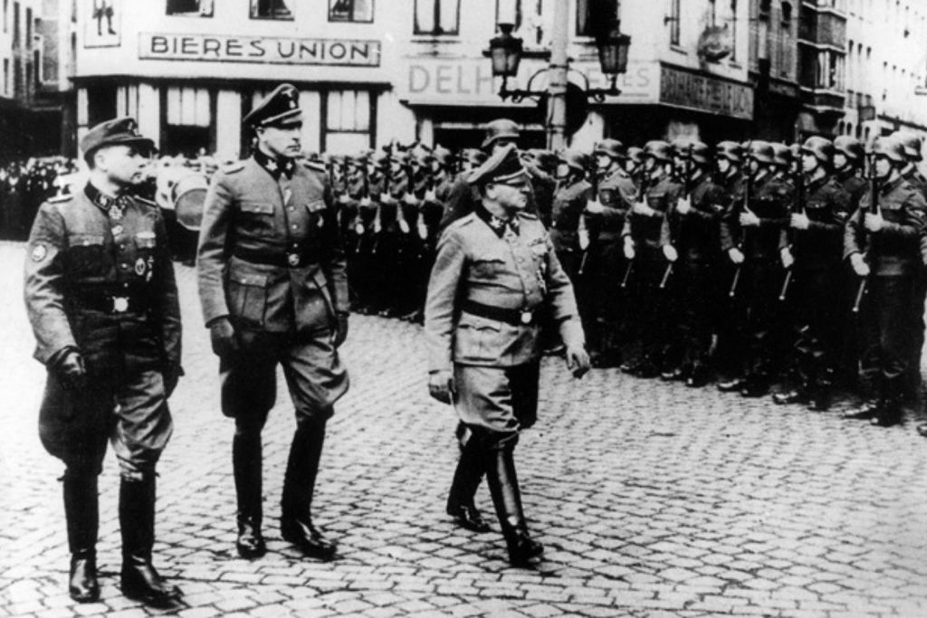 El 2 de abril de 1944, durante una revista a las tropas de las SS en una plaza urbana, el oficial Léon Degrelle desfiló junto a los voluntarios valones, acompañado por el general de las SS Josef “Sepp” Dietrich y Richard Jungclaus